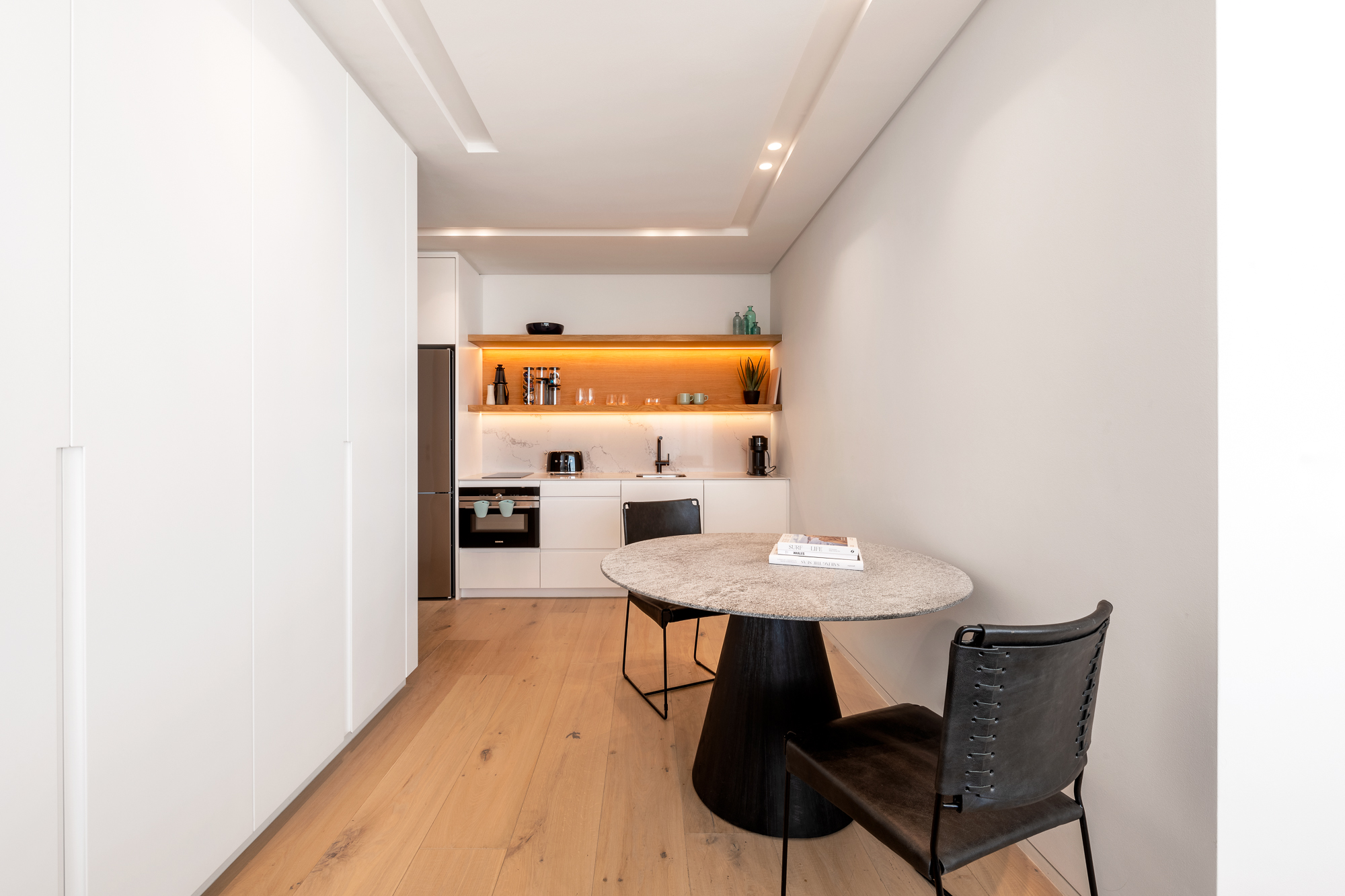 Mare Suite dining nook with round stone table and kitchenette – Riva One, Camps Bay