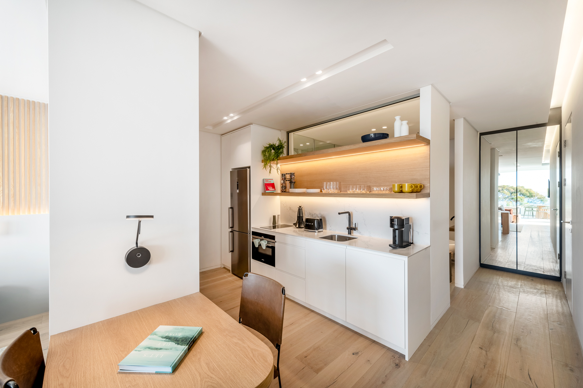 Sole Suite kitchenette with open wood shelving and dining table – Riva One, Camps Bay