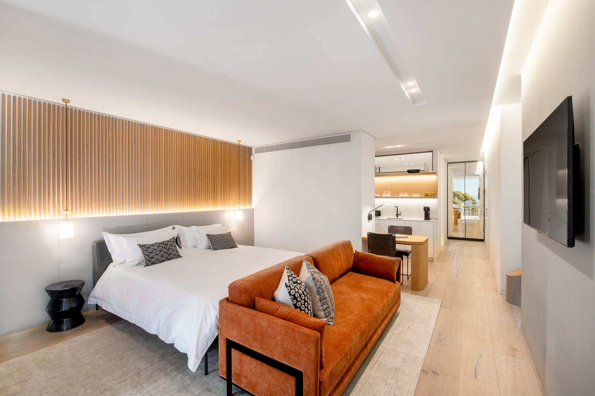 Sole Suite living area with wood-slat headboard wall and terracotta sofa – Riva One, Camps Bay