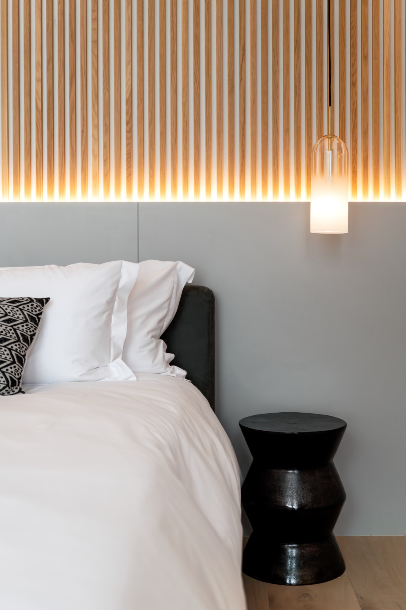Sole Suite bedside pendant light against the wood-slat headboard – Riva One, Camps Bay